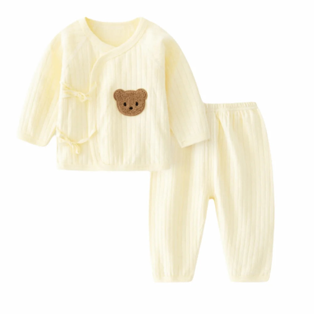 Light yellow baby outfit with a bear design on a cream background
