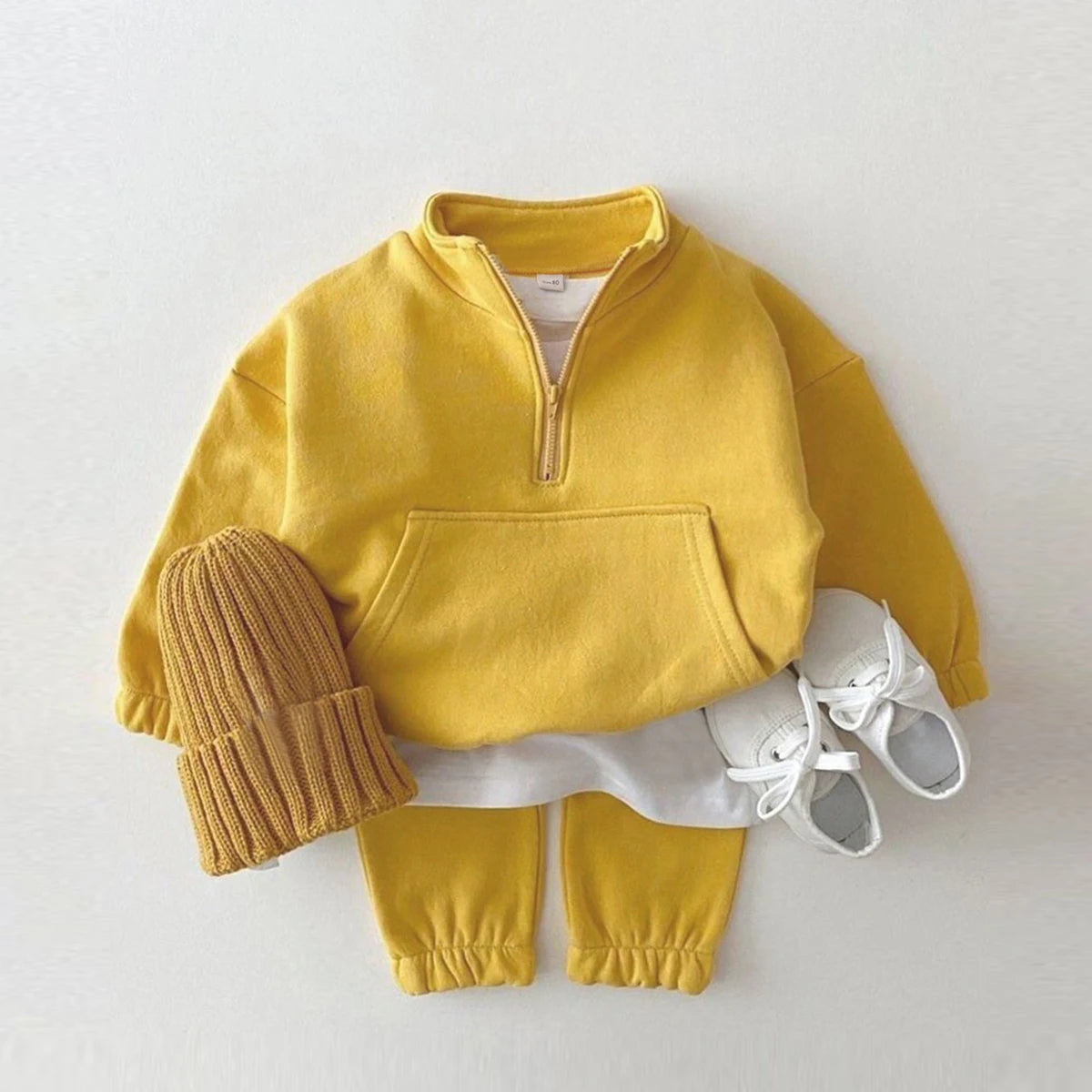 Yellow and mustard children's outfit with a mustard hat and white shoes on a white background