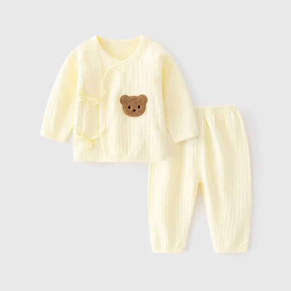 Cream baby outfit with a bear emblem on a light gray background
