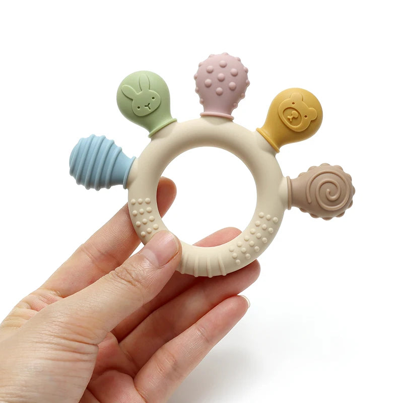 Colorful baby teething ring held in a hand against a white background