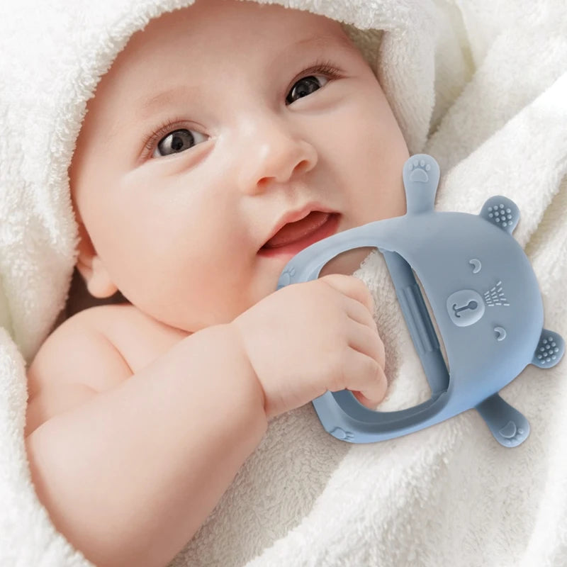Baby holding a blue teething toy with a soft white blanket