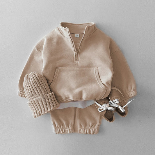 Children's beige outfit with a sweater, hat, and shoes on a light gray background