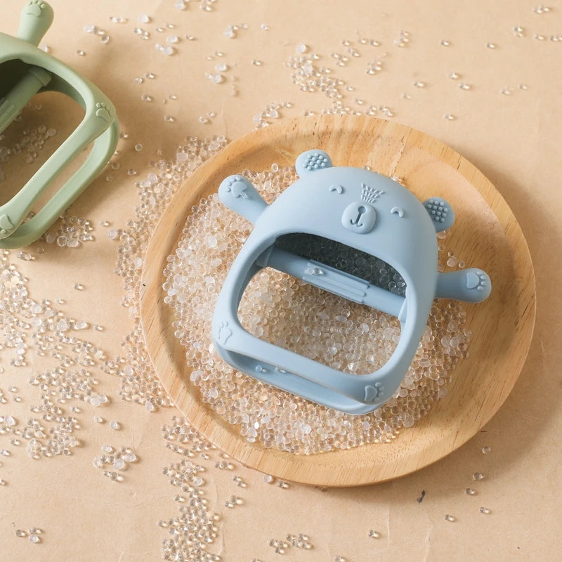Blue bear-shaped teether on a wooden plate with a beige background