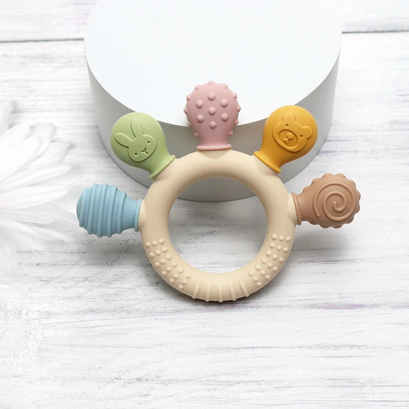 Colorful baby teething ring on a light wooden surface