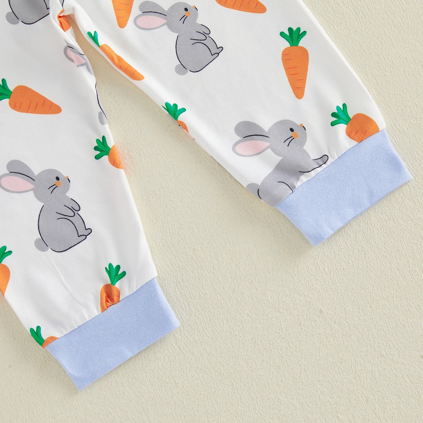 Two fabric swatches with rabbit and carrot patterns on beige and white 
background