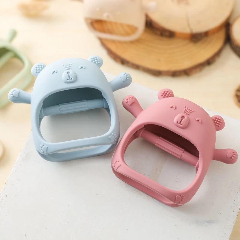Two bear-shaped silicone clips, one blue and one pink, on a light surface.