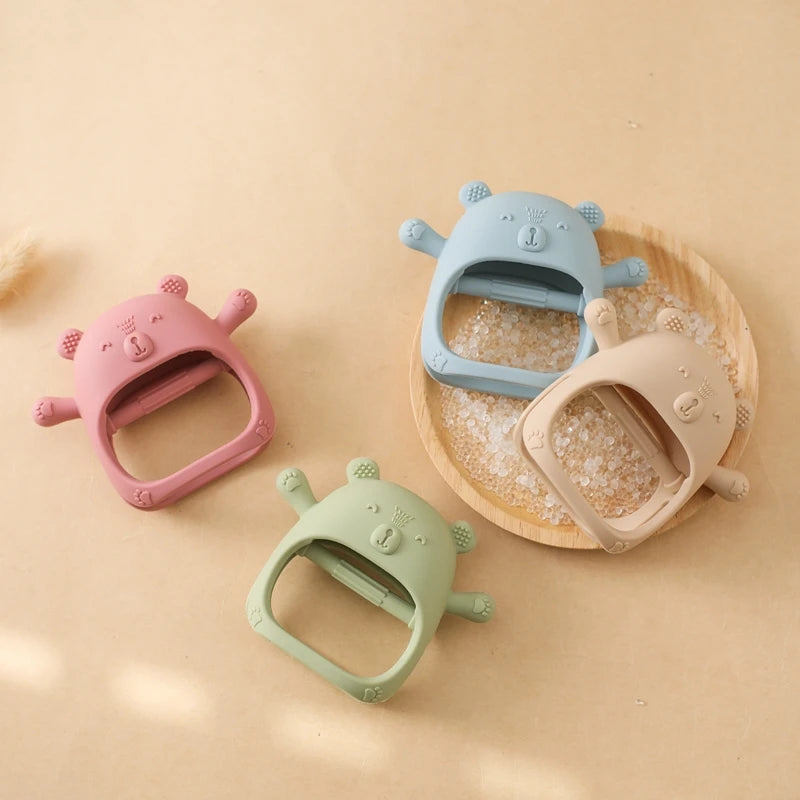 Four colorful silicone sand toys shaped like animals on a beige surface.
