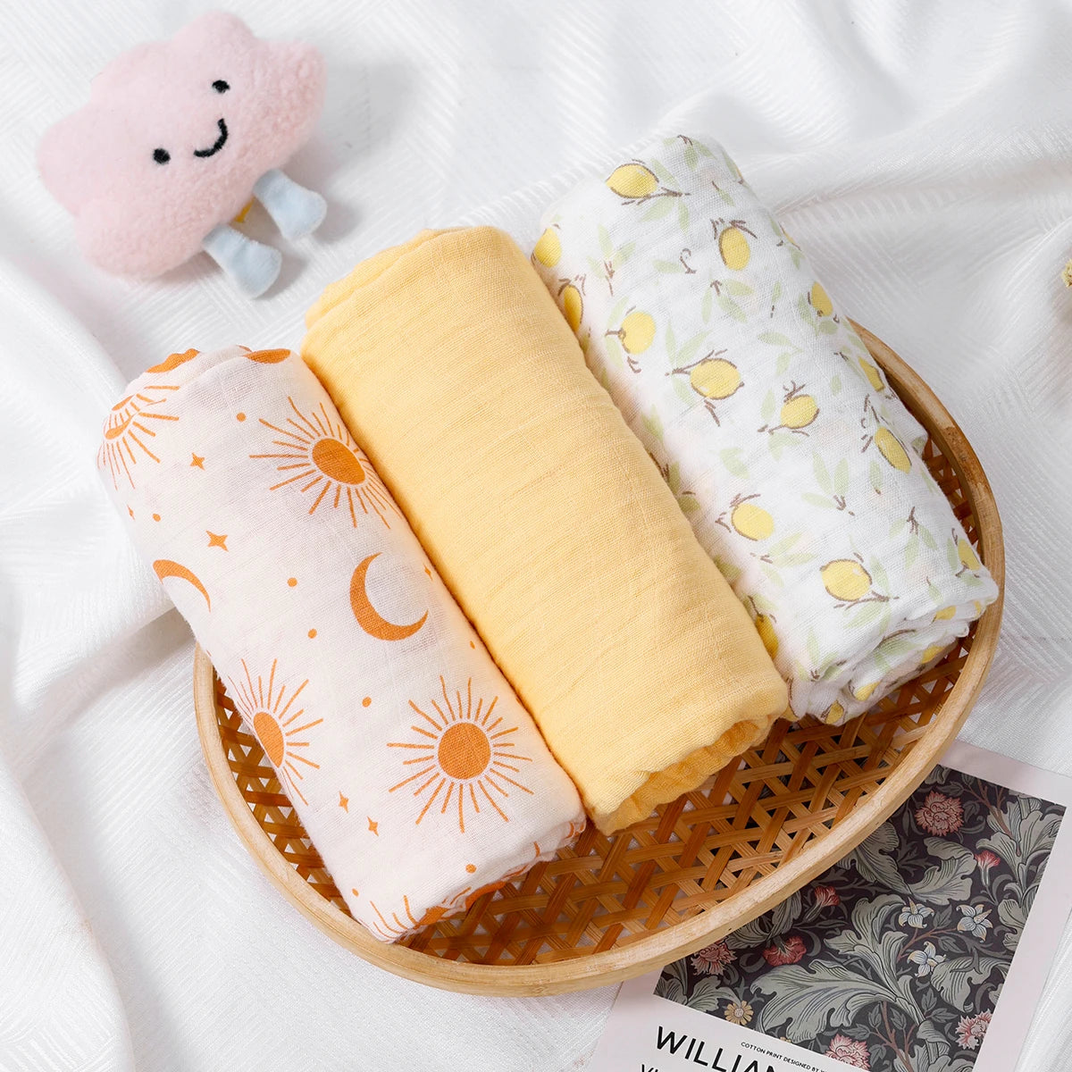 Three rolled-up baby blankets with patterns in a wooden basket on a white background