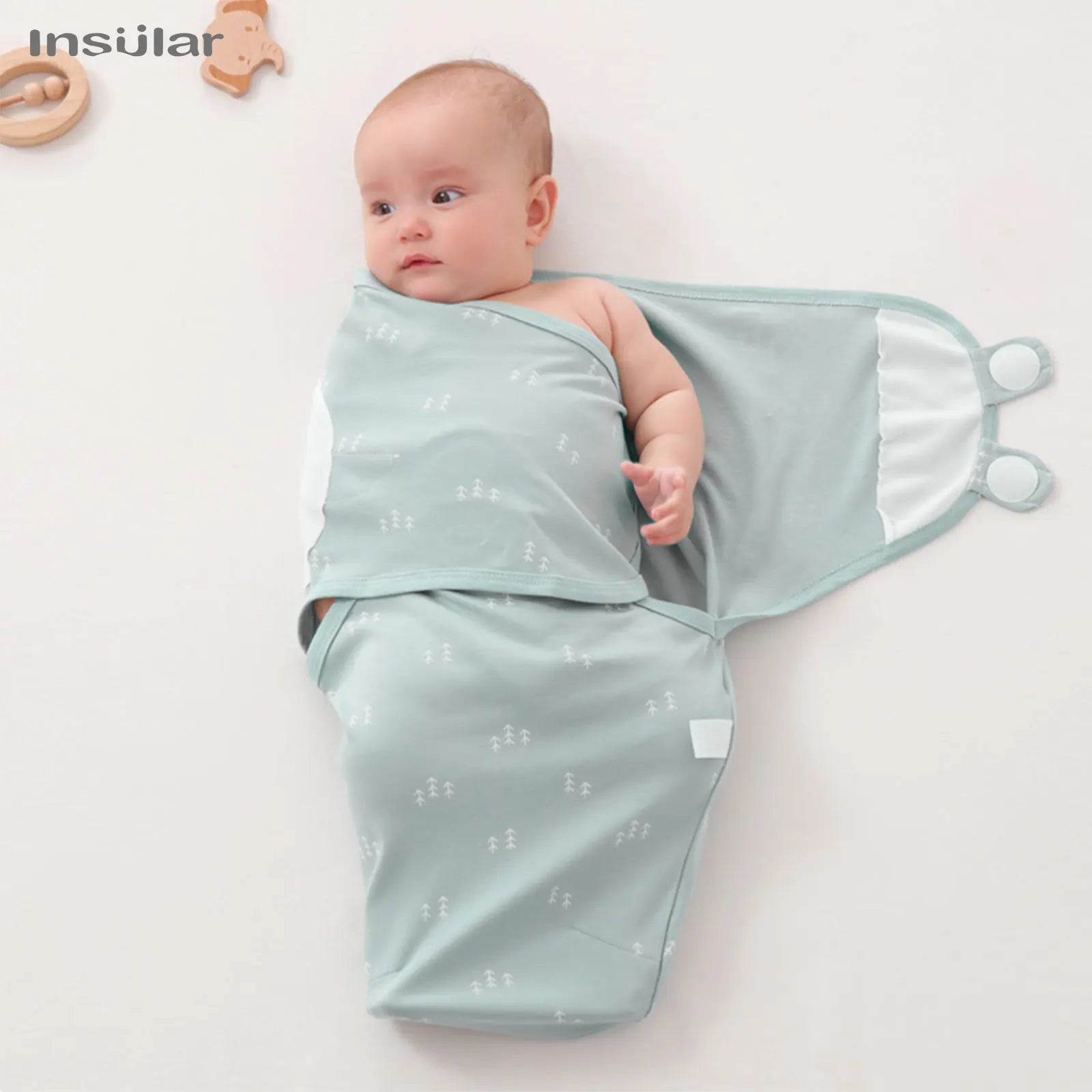 Baby wrapped in a light blue swaddle with white patterns on a white background
