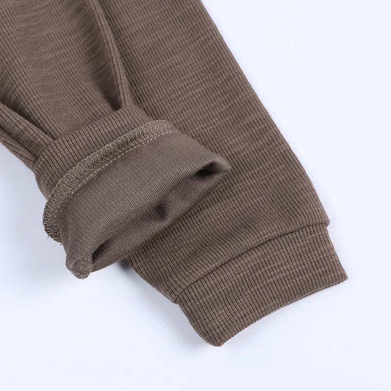 Close-up of a brown ribbed sweater sleeve on a white background