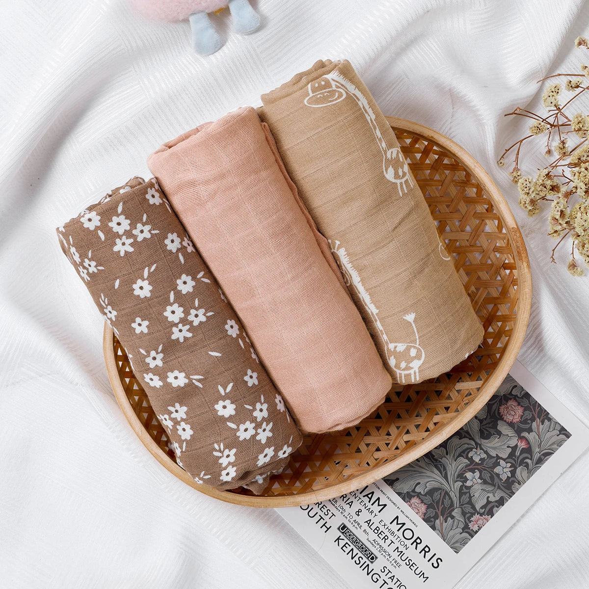 Three folded fabric swatches in a wooden basket on a white surface with a newspaper underneath.
