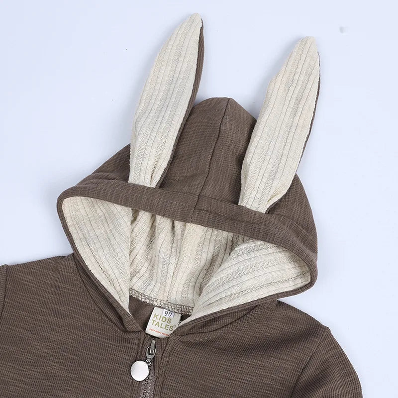 Brown baby onesie with bunny ears on a light blue background