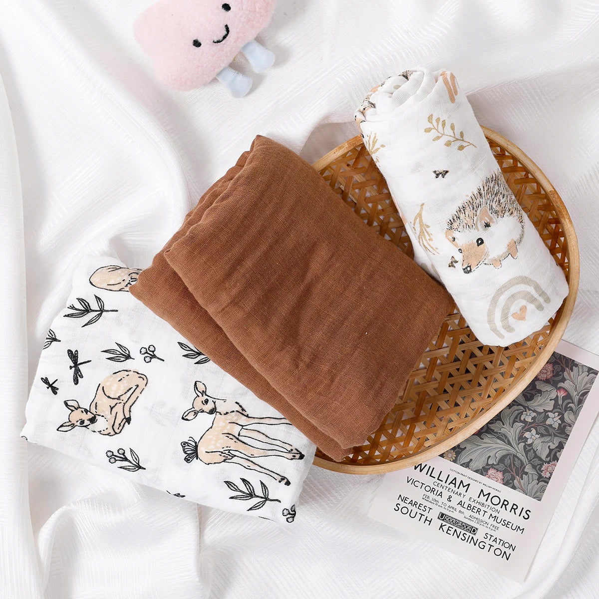 Baby blankets with animal prints on a wooden tray on a white background