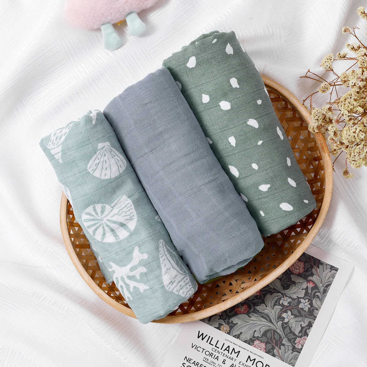 Three folded fabrics with patterns in a woven basket on a white surface.