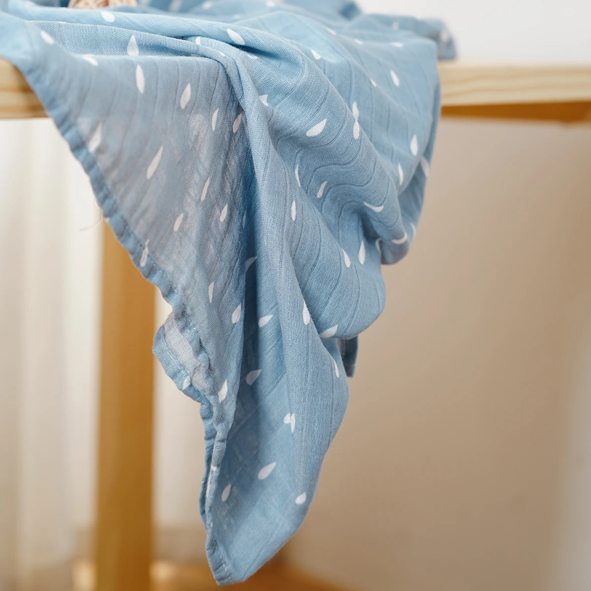 Blue textured fabric draped over a wooden surface with a blurred background
