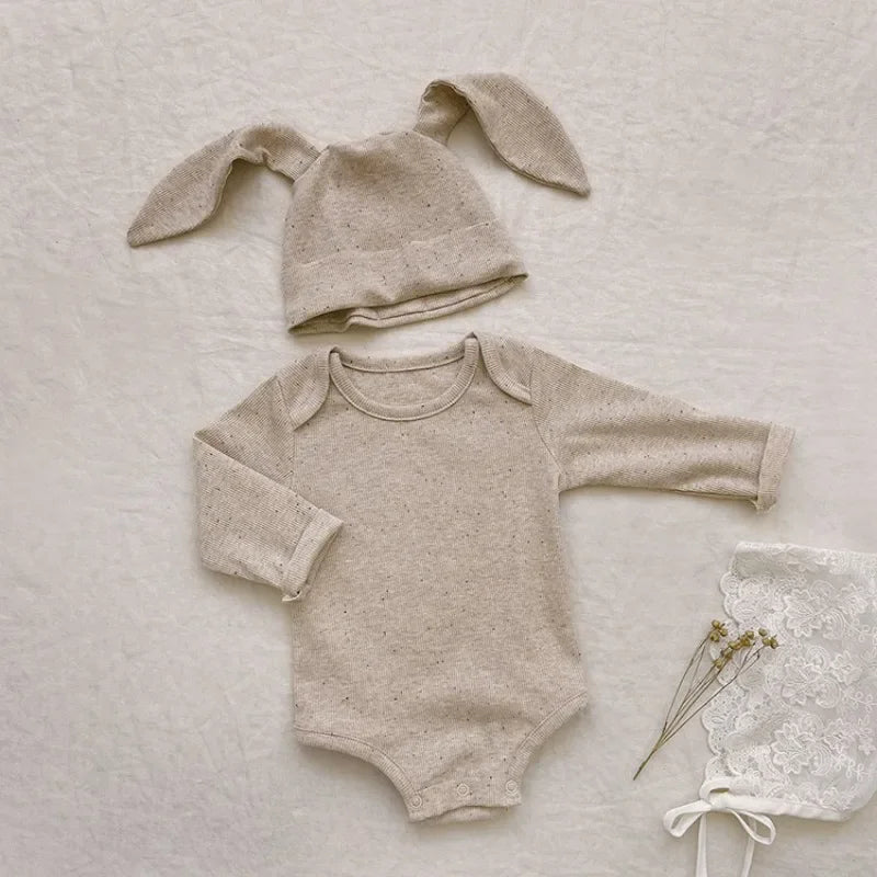 Baby outfit with onesie and bunny ears hat on a textured surface