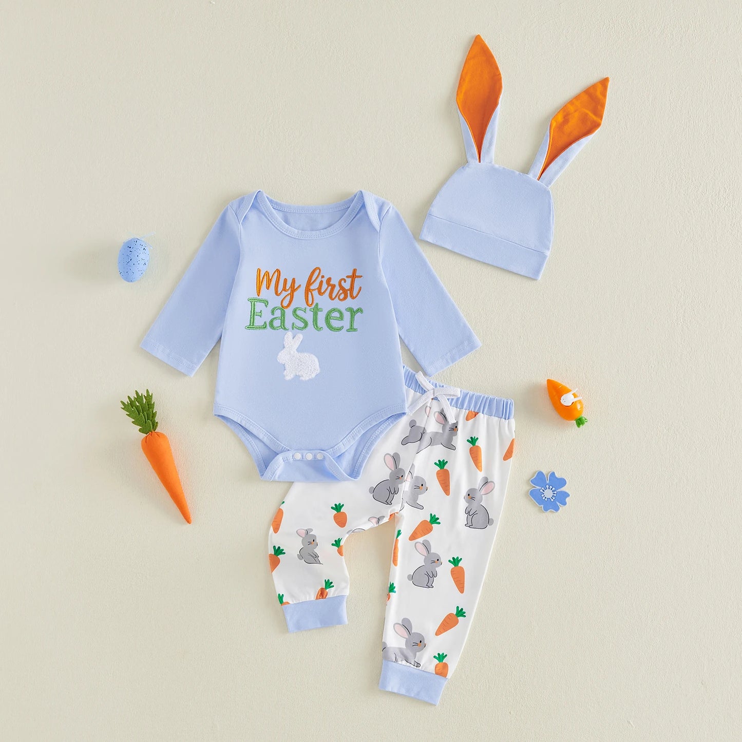 Baby Easter outfit with blue onesie, hat, and pants on a beige and white background