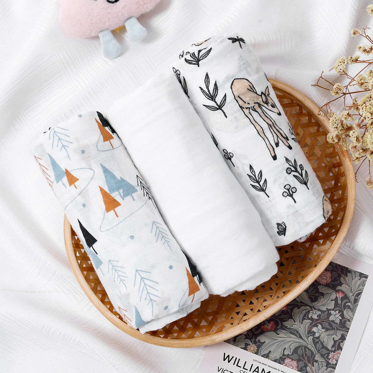Two baby swaddle blankets with animal prints in a woven basket on a white surface.