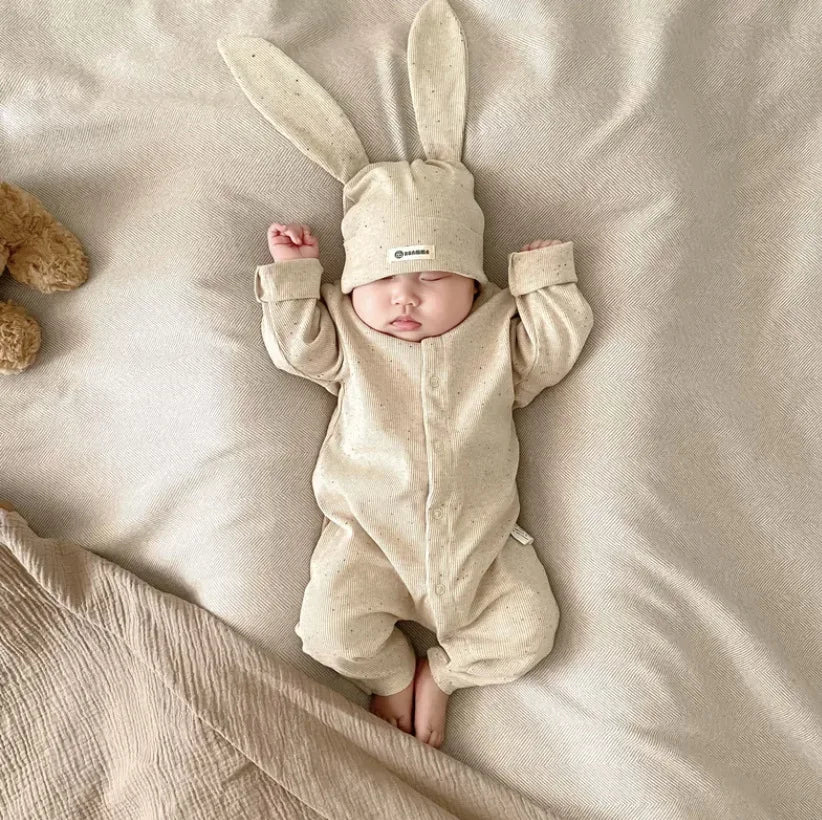 Baby in a beige bunny costume lying on a soft surface