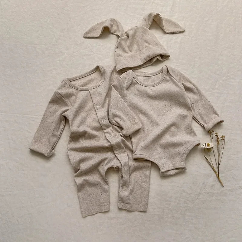 Beige baby outfit with bunny ears on a light background