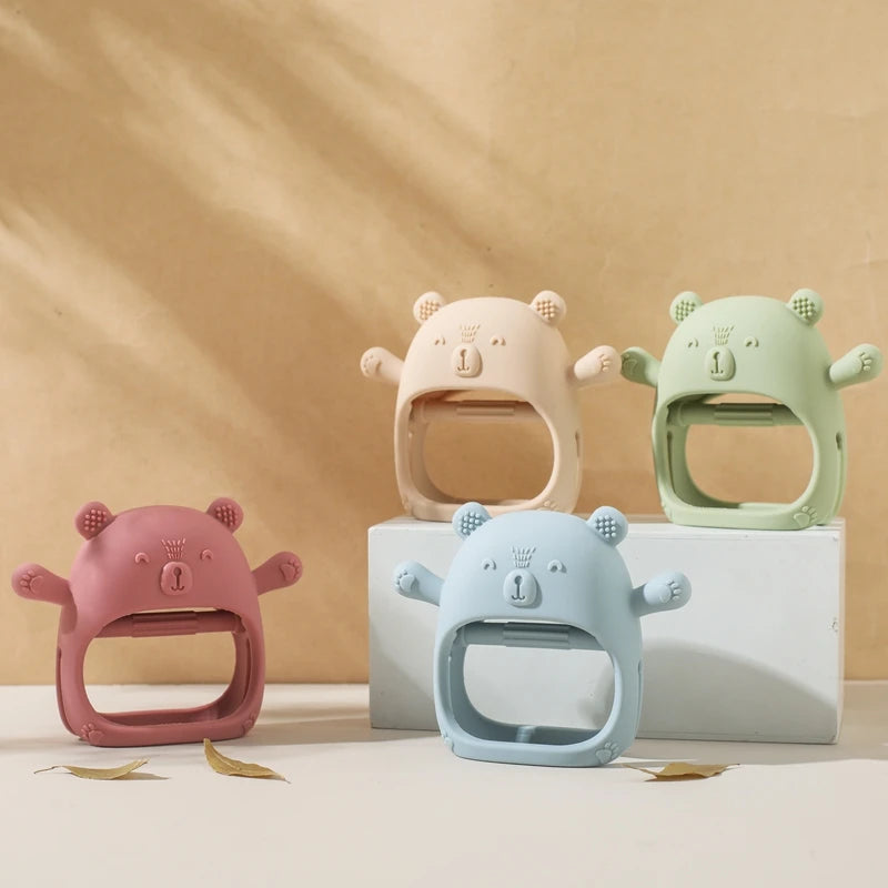 Four colorful bear-shaped baby teething rings on a beige background